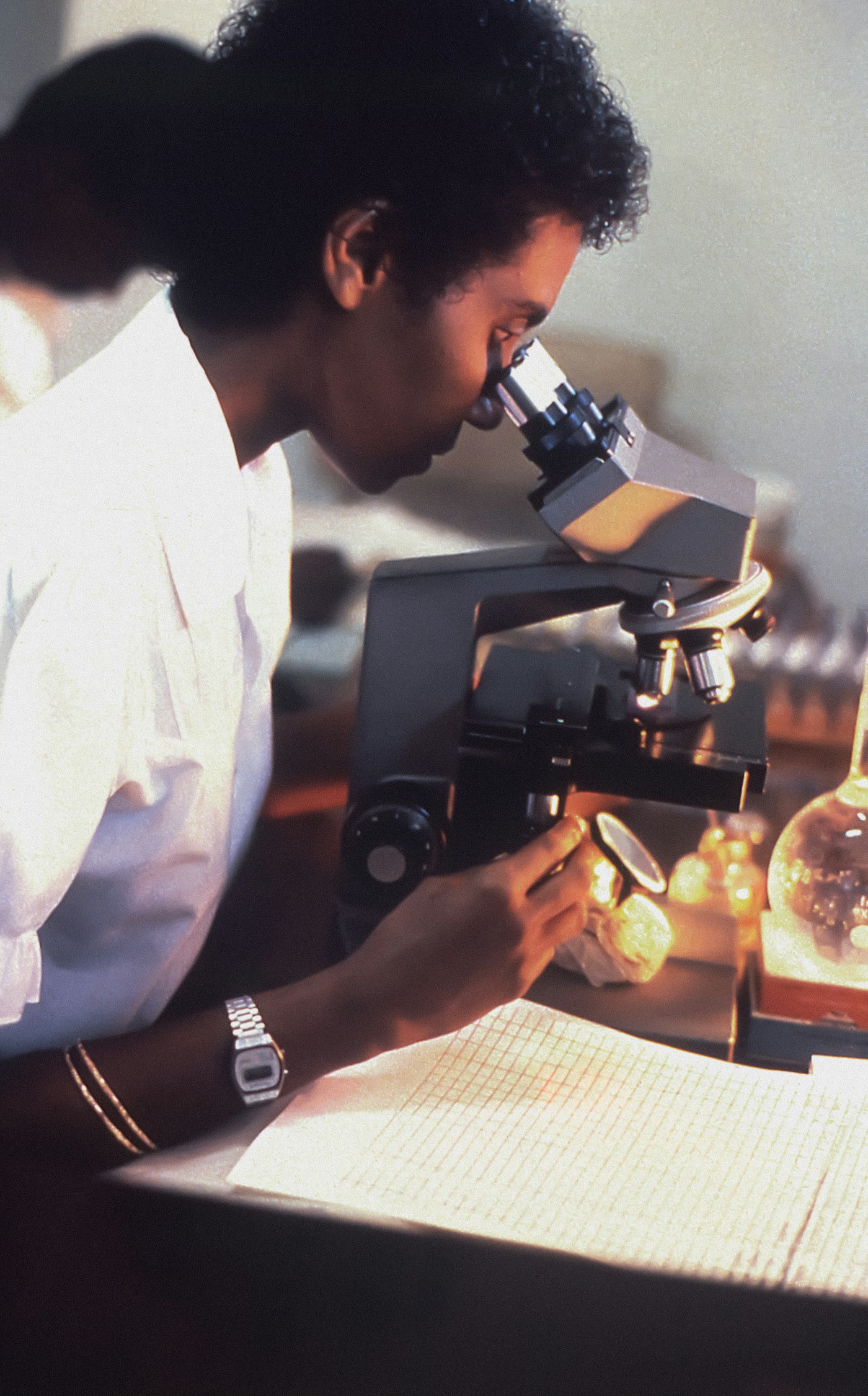 African laboratory scientist examining a sample under a microscope